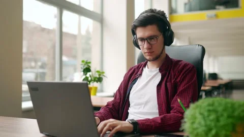 Young stylish customer support service worker removes headphones, looking at Stock Footage 219799970