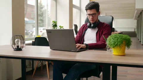 Young stylish freelancer working with laptop then looking at camera. Office Stock Footage 220725454