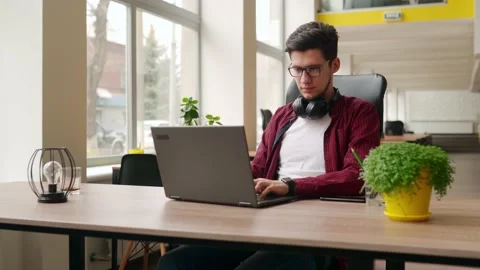 Young stylish freelancer working with laptop then looking at camera. Office Stock Footage 221605626