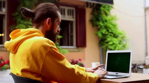 Young stylish handsome man using laptop sitting in cafe outside enjoying sunshin 스톡 동영상 132170991