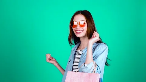 Young stylish lady after shopping on a green background. Stock Footage
