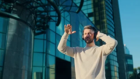 Young stylish man with beard dancing to music in urban backdrop Video stock 317554691