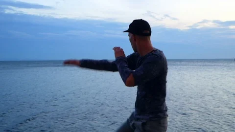 Young stylish man dancing by the sea at sunset Stock Footage 96621158