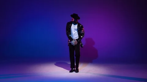 Young stylish man dancing in style Michael Jackson, spotlight on a blue Stock Footage 122072342
