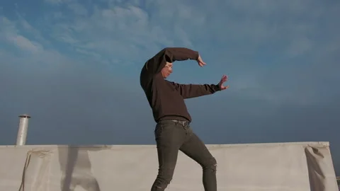 Young stylish man dancing on the wet brilliant floor after the rain on the Stock Footage 105463795