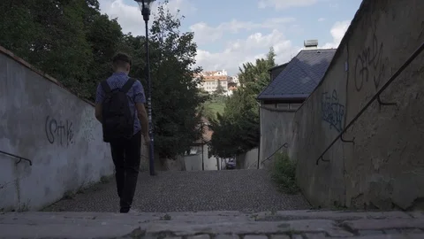 Young stylish man goes down the stairs in the alley of Prague 스톡 동영상 115766375