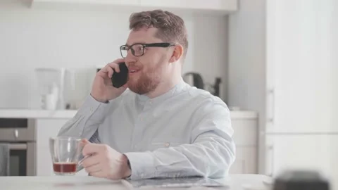 Young stylish man in light clothes communicates on the phone for breakfast in Video stock 156958161
