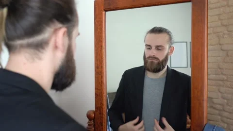 Young Stylish man looking at himself into a mirror putting on a stylish suit Video stock 147894536