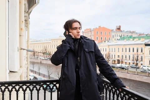 Young stylish man talking on mobile phone on balcony. Fashionable guy Stock Photos