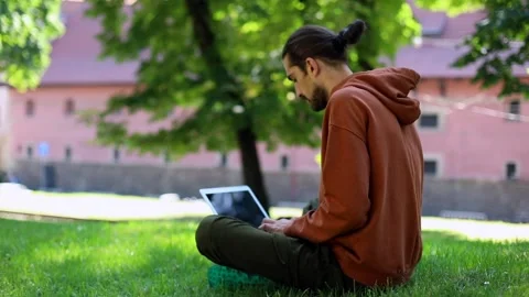 Young stylish man using modern laptop outside in summer green park searching Stockbeeldmateriaal 138881741
