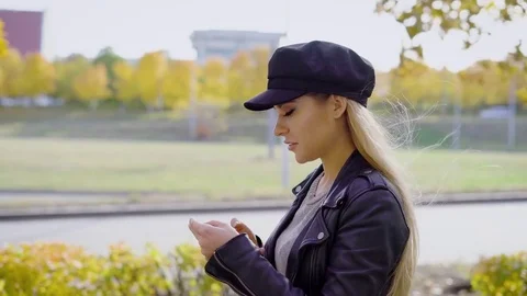 Young stylish model having stroll in urban park using smartphone Stock Footage 81577380