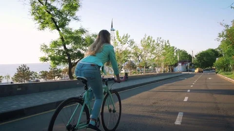 Young stylish woman cyclist enjoying fixed gear bike riding outdoors at sunrise Stock Footage