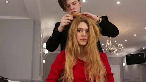 Young stylist men does hair styling to a beautiful girl in a beauty salon Stock Footage