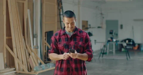 Young success woodworker using a mobile phone while standing in the workshop Video stock 199619519