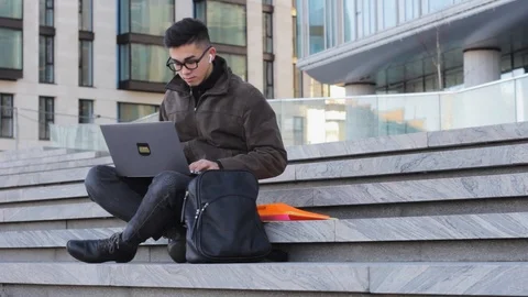 Young successful Asian student programmer sit on the steps of the office laptop 스톡 동영상 124103313
