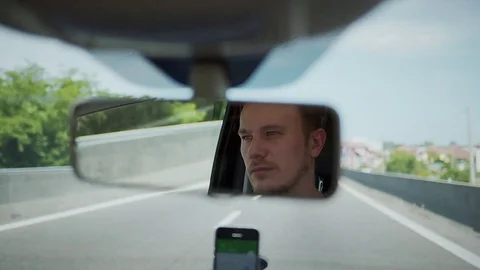 Young successful driver looking in rear view mirror Stock Footage 77620812