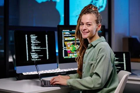 Young successful female programmer looking at camera by workplace Stock Photos