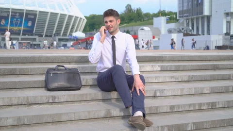 A young successful man is sitting on the steps and talking on the phone. White Stock Footage 91493823