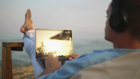 Young successful man working with laptop in the beach bar by the sea. Freelan Video stock 154991504