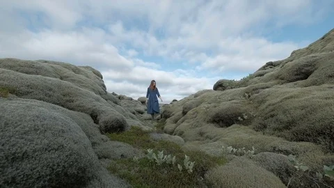 Young summer beauty. Red haired girl in blue dress on Green mossy icelandic Stock Footage 80616304