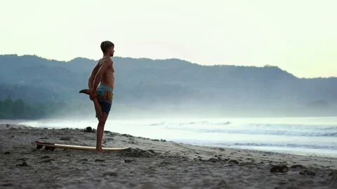 Young surfer man doing yoga exercise for surfing at a tropical beach.  Stock Footage 108565146