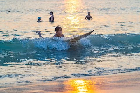 Young Surfer Riding Waves at Sunset Stock Photos