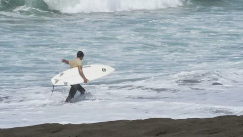 Young surfer walking on the beach with his surfboard under his arm Stock Footage 100089248