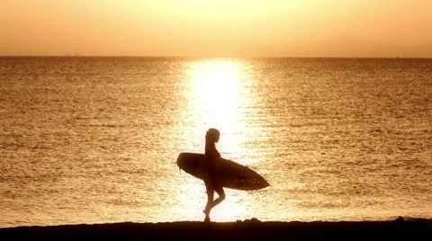 Young Surfer Walking Out To Enjoy The Surf At Sunset Видео 42960465