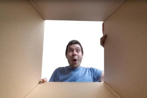Young surprised man is looking inside cardboard box. Foto stock