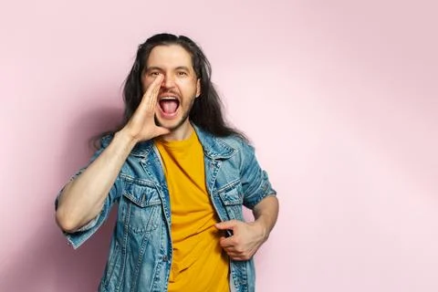 Young surprised man screaming with hand near mouth. Isolated on pastel pink.. Stock Photos