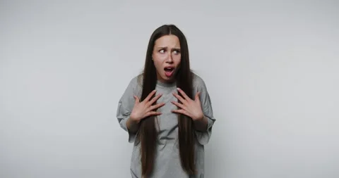 Young surprised woman is shown holding her hands to her chest, expressing a.. Stock Footage 314338317