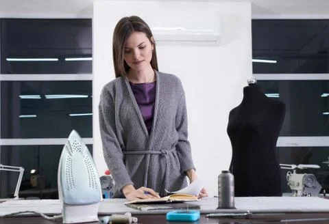 Young tailor at her workshop designing new clothes, atelier studio Stock Photos