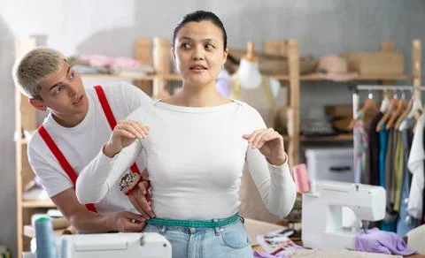 Young tailor measuring female client in sewing workshop Stock Photos