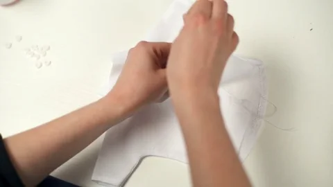 Young tailor sews buttons on small white tiny shirt for the stuffed animals Video stock 72705872