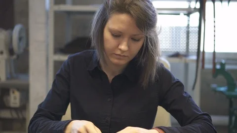 Young tailor tying up and cutting thread on leather detail in sewing studio. Stock Footage 120406877