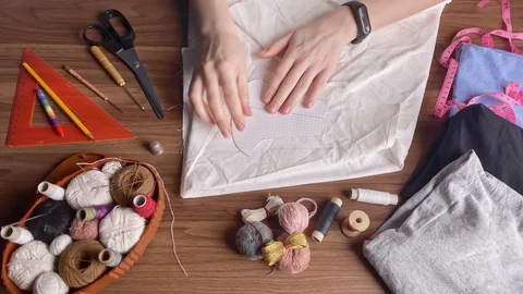 Young tailor uses red pencil to transfer patterns reusable protective mask on Stock-Footage 128362954