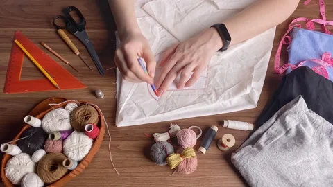 Young tailor uses red pencil to transfer patterns reusable protective mask on Stock-Footage 128362972
