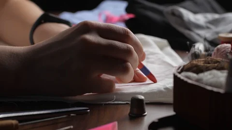 Young tailor uses red pencil to transfer patterns on white tissue. Close up w Stock-Footage 128363371