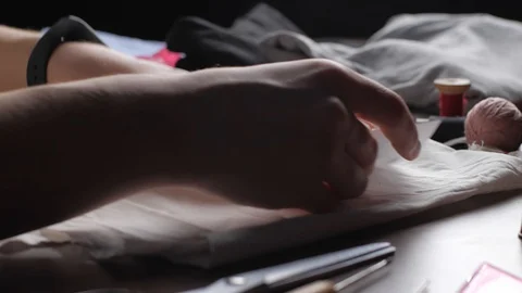 Young tailor uses red pencil to transfer patterns on white tissue. Close up w Stock-Footage 128363394