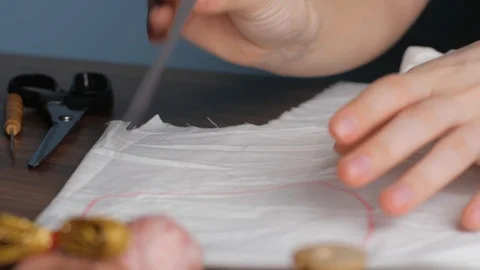 Young tailor uses red pencil to transfer patterns on white tissue. Close up w Stock-Footage 128363414