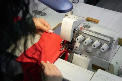 Young tailor using professional overlock sewing machine in workshop studio Stock Photos
