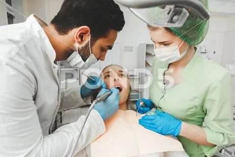 Young talented dentist and his assistant nurse at work Stock Photos