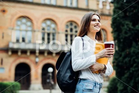 Young talented female student dressed in casual clothing walking around city. Stock Photos