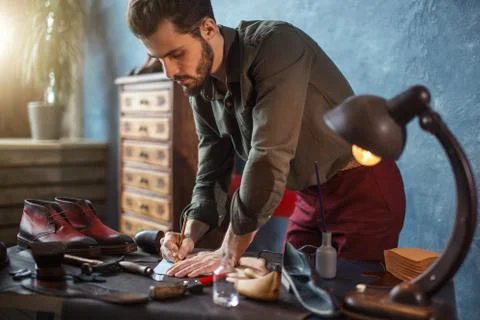 Young talented hoemaker using his knowledge of the fashion industry Stock Photos