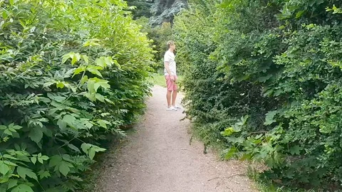 Young tall blond guy walks in the park along the path between the bushes 動画素材 104444418