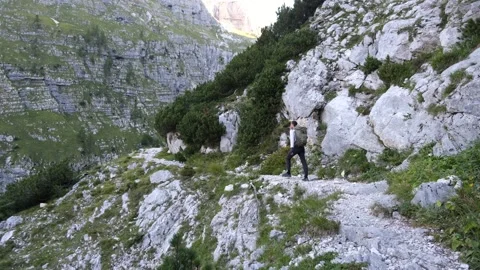 Young tall man hiking on side of rocky green mountain with a backpack Stock Footage 161906019