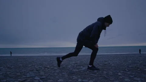 Young tall person is doing warm up. Training on open air at nasty weather Stock Footage 147724963