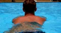 Young Tanned Muscular Man Swimming in Blue Pool in Slow Motion. HD Footage