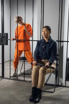 A young taskmaster in uniform sits on a chair next to the camera of a blonde Stock Photos