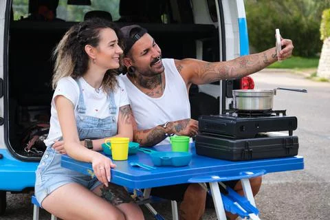 Young tattooed couple take a selfie after have lunch near by the van. Stock Photos